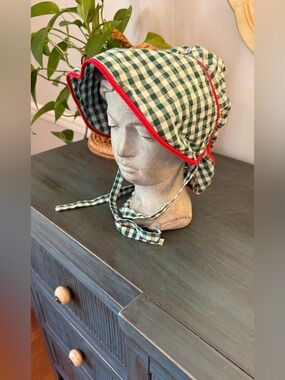 Green and White Gingham check bonnet with red trim along brim. Tie chin strap.